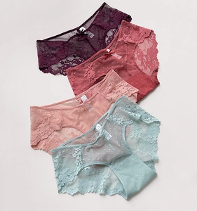 Dettaglio di slip in pizzo a vita bassa con ricamo floreale e piccoli fiocchi in raso