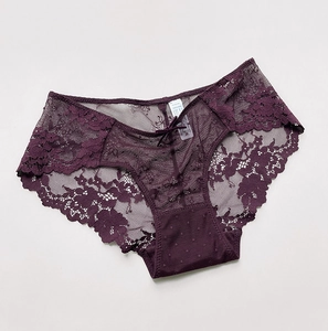 Dettaglio dello slip in pizzo viola scuro con trama floreale e un piccolo fiocco centrale
