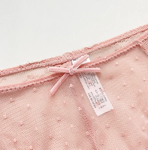 Dettaglio degli slip in rete rosa con trama a pois e piccolo fiocco in velluto in vita