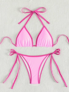Flat lay of pink two-piece bikini set with contrast trim on white textured backdrop