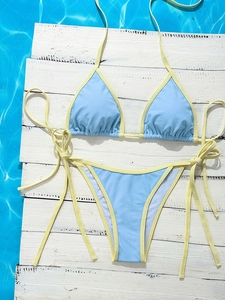 Detailed flat lay of blue and yellow bikini set on white wood with pool water background