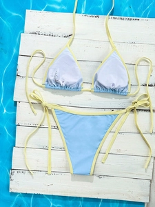 Detail of color-block bikini set with blue fabric, yellow trim, and care label on wood