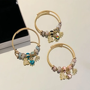Detailed close-up of golden cable bracelets with heart and bear charms on reflective surface
