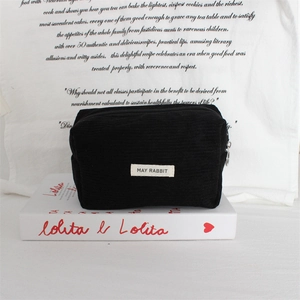 Detail of black corduroy cosmetic pouch with May Rabbit label and metal zipper ring