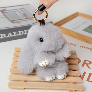 Detailed close-up of a fluffy grey plush rabbit keychain with premium gold hardware and texture