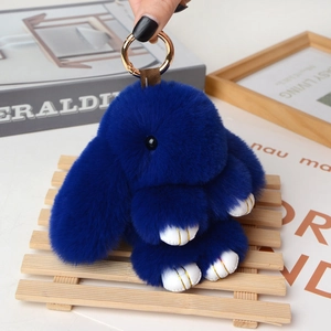 Close-up of fluffy dark blue plush bunny keychain with gold claws and spring hook