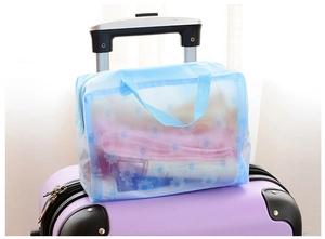 Blue translucent daisy pattern waterproof toiletry bag attached to suitcase handle