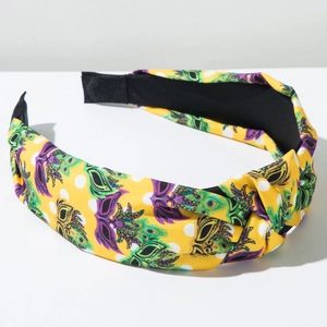 Detail of yellow carnival headband with festive mask print and top knot texture