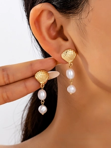 Close-up of elegant gold shell earrings with hanging double white baroque pearls