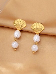 Close-up of golden shell earrings with baroque pearls on elegant champagne silk fabric