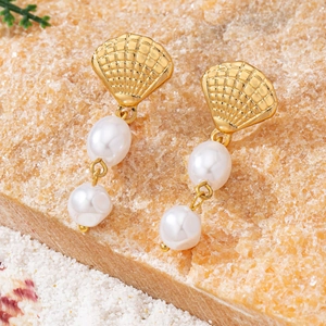 Elegant gold shell earrings with hanging double pearls on natural stone and white sand