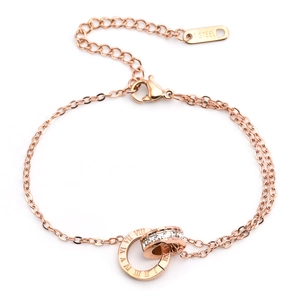 Detail of rose gold layered bracelet featuring interlocking roman numeral and crystal rings