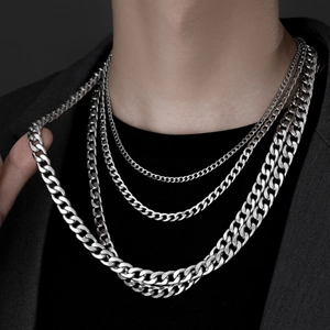 Detail of four-piece silver stainless steel Cuban link chains layered on a male model