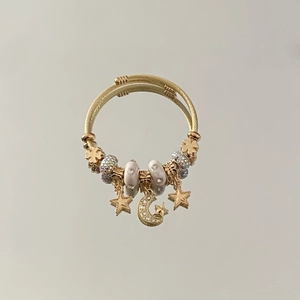 Macro detail of golden twisted cable bracelet with star, moon charms and crystal beads