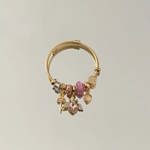 Detail of gold-plated bangle featuring pink winged heart charm and crystal beads