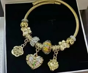Close-up of golden beaded bracelet with heart and rose charms in a display gift box