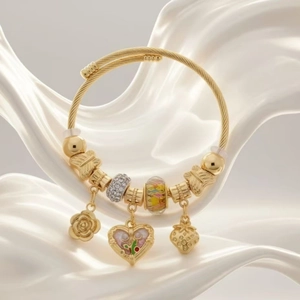 Detailed close-up of a golden charm bracelet featuring flower, strawberry and heart charms