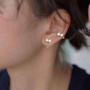 Close-up of sparkling 925 silver bow stud earrings with zircons on a woman's ear