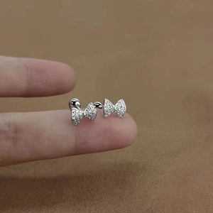 Macro shot showing 925 sterling silver bow earrings with zircons held in hand