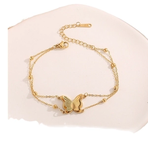 Double-layer gold butterfly bracelet with metallic beads on white pedestal