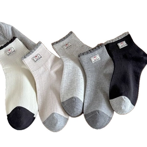 Five pairs of rib-knit crew socks with scalloped edges and cute dog labels in neutral colors