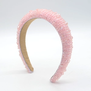 Dettaglio di perline di cristallo rosa fatte a mano su un cerchietto imbottito in velluto