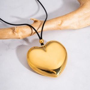 3D hollow heart pendant necklace in 18K gold finish hanging on a natural wooden branch