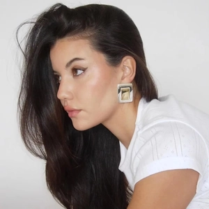 Detailed view of minimalist square stainless steel earrings with gold plating on model