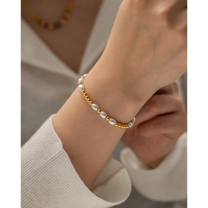 Gros plan de perles dorées 18K et de perles blanches sur un bracelet élégant