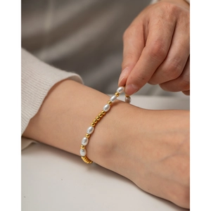 Vue détaillée d'un bracelet élégant en perles et or porté sur un poignet