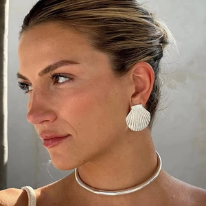 Detail of silver shell-shaped earrings and minimalist metal choker on a model