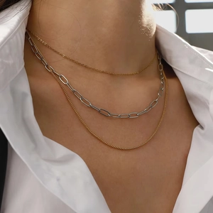 Three-layer gold and silver necklace set styled on a model wearing a white shirt
