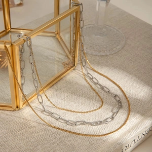 Detail of layered gold and silver mixed metal chains draped over a glass display box