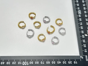 Macro shot of gold and silver hoop earrings with cubic zirconia on a measuring scale