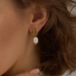 Détail de boucles d'oreilles conque en or 18 carats avec pendentifs perles sur un modèle