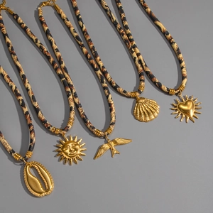 Detail of five gold charms including sun and shell on leopard print fabric cords