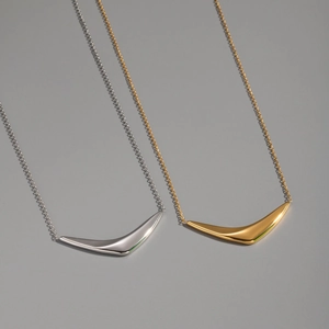 Macro view of minimalist geometric arc pendants in polished gold and silver finishes
