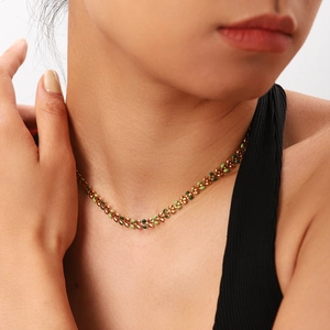 Close-up of vintage gold leaf necklace with green enamel on a female model's neck