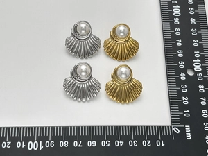 Confronto dettagliato di orecchini a conchiglia oro e argento con perle e righello