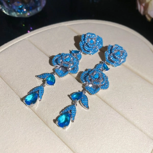 Close-up of blue teardrop zircon tassels on silver flower earrings showing luxury details