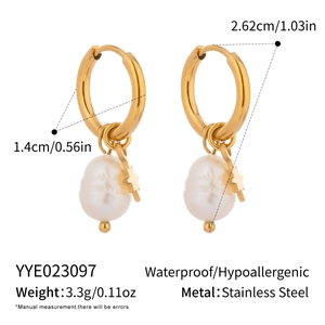 Detailed macro view of gold star charms and white freshwater pearls on steel earrings