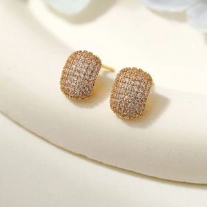 Close-up of geometric pavé diamond stud earrings in gold finish with sparkling zircons