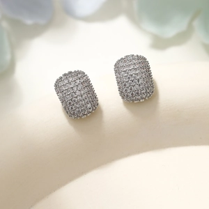 Macro view of geometric silver earrings with pavé diamond setting on a textured base