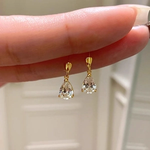 Close-up of elegant gold pear-cut cubic zirconia drop earrings held between fingers