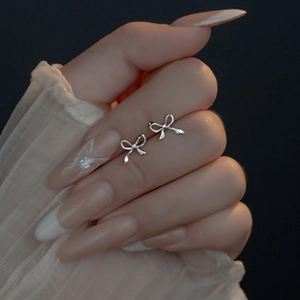 Close-up of elegant silver bow stud earrings with polished finish on a person
