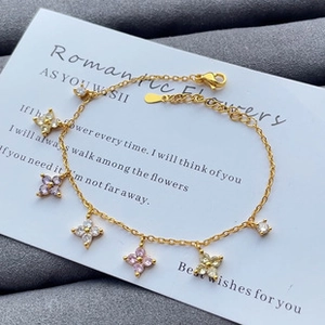Close-up of gold chain bracelet with flower pendants and purple zircon stones