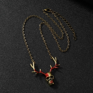 Close-up of gothic gold skull necklace with antler horns and red enamel accents