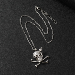 Detailed close-up of punk skull and snake pendant necklace on black leather background