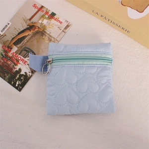 Close-up of light blue quilted heart coin purse with round metal zipper and side strap