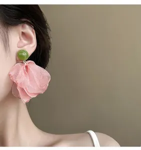 Detail of model wearing pink petal chiffon earrings with green marble stud details